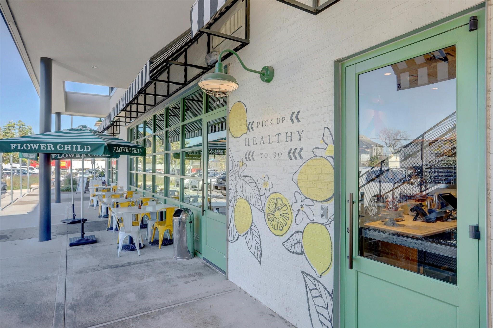 Flower Child restaurant storefront with mint-green doors, a lemon mural, and outdoor patio seating.