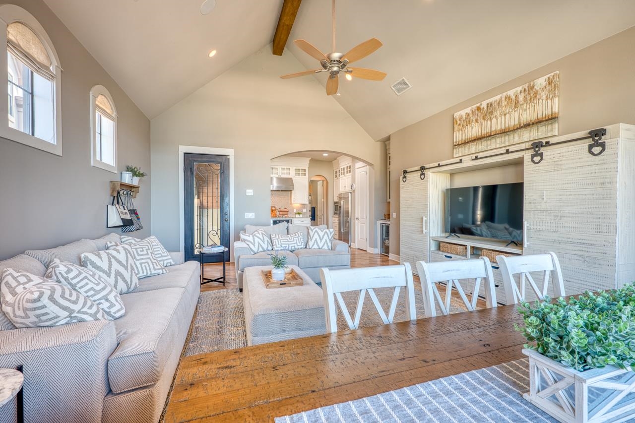 Living room with vaulted ceiling, exposed beam, arched windows, and sliding barn-door media cabinet.