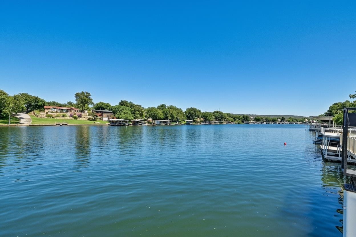 Wide lake view with homes along the tree-lined shore and docks extending over the water.