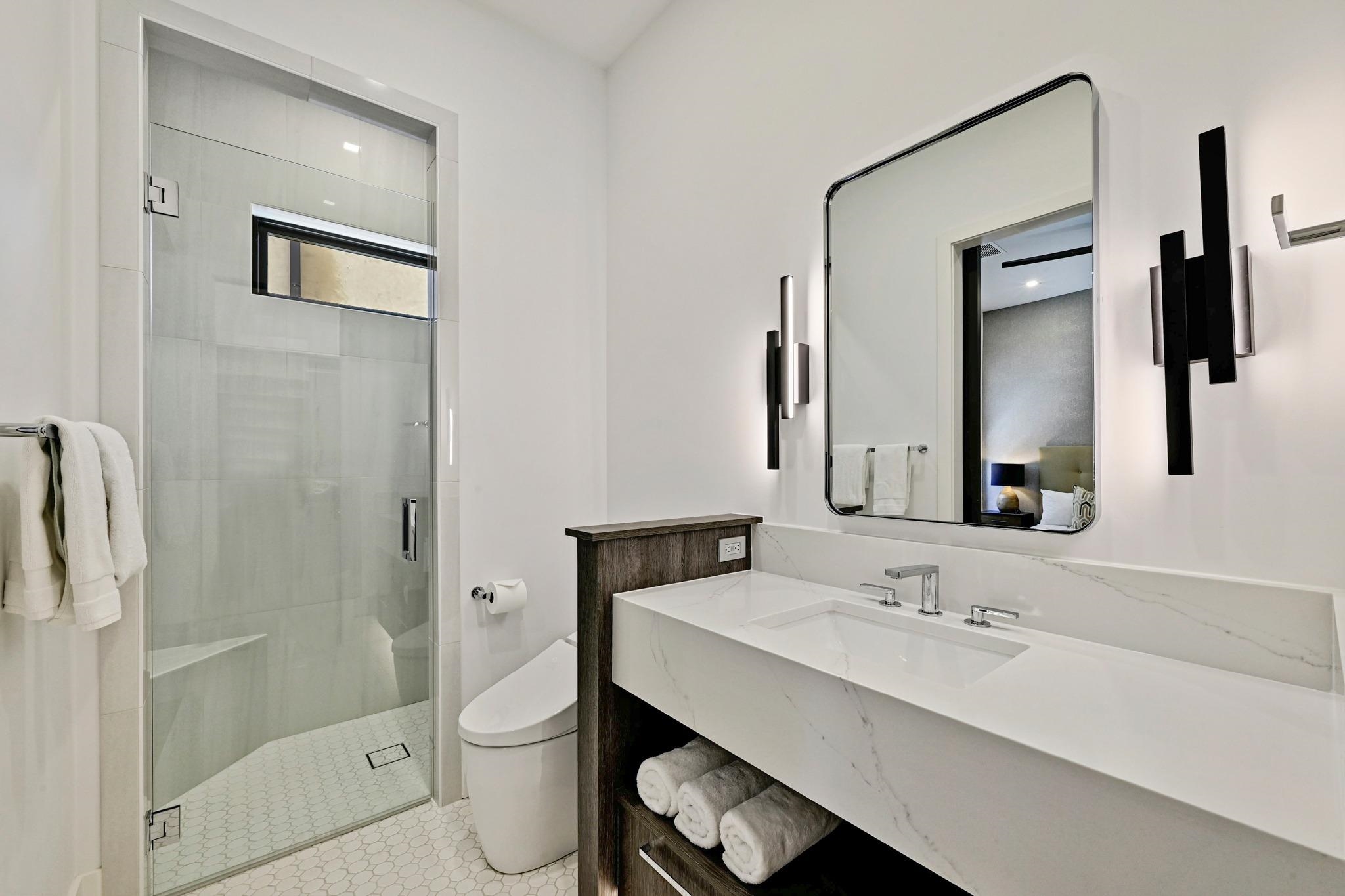 Modern bathroom with a glass walk-in shower and long white stone vanity.
