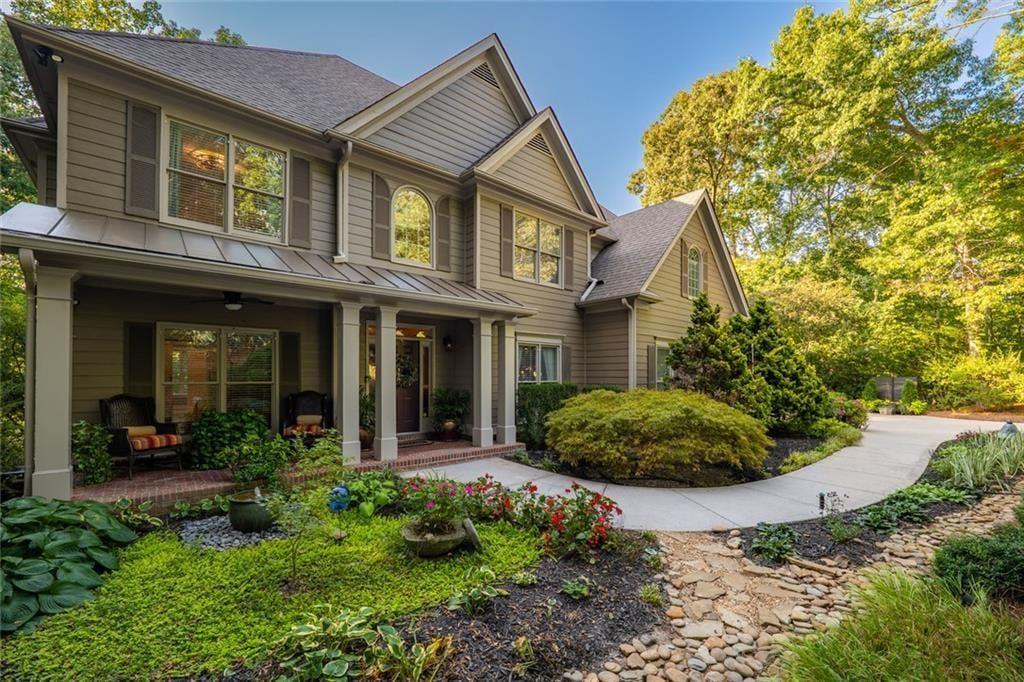 Two-story home with a covered porch, landscaped garden, and curved walkway.