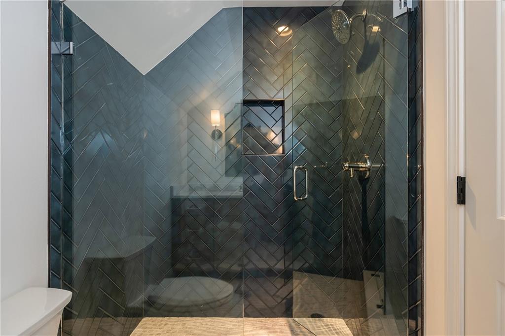 Walk-in shower with dark herringbone tile, brass fixtures, and a recessed niche.