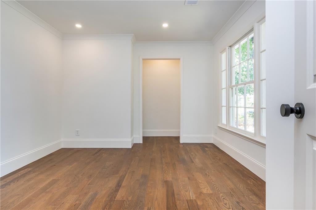 Empty room with hardwood floors and tall multi-pane windows.