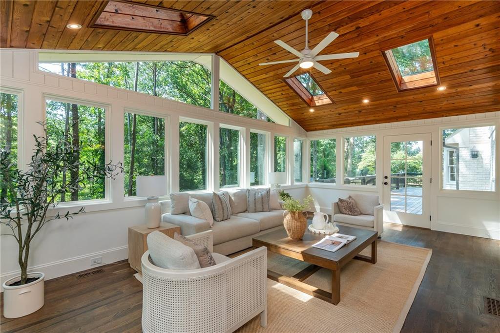 Sunroom with expansive windows, a vaulted wood ceiling, and neutral seating.