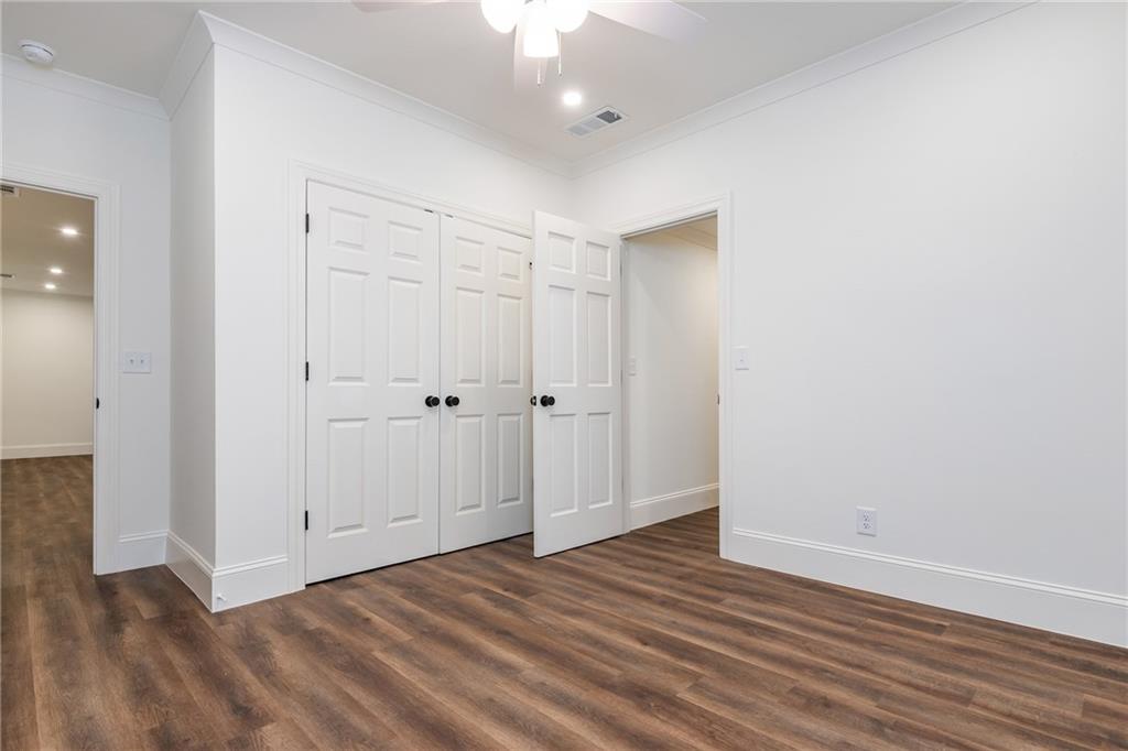 Empty room with paneled closet doors and dark wood-look flooring.