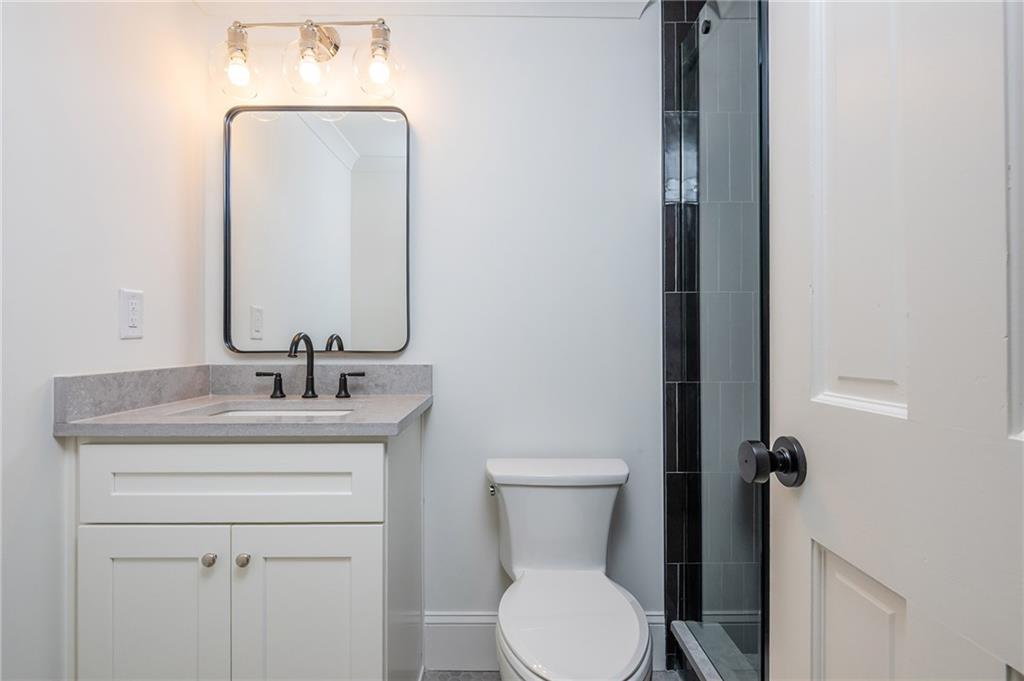 Bathroom with a white vanity, black fixtures, and a glass shower with dark tile accents.