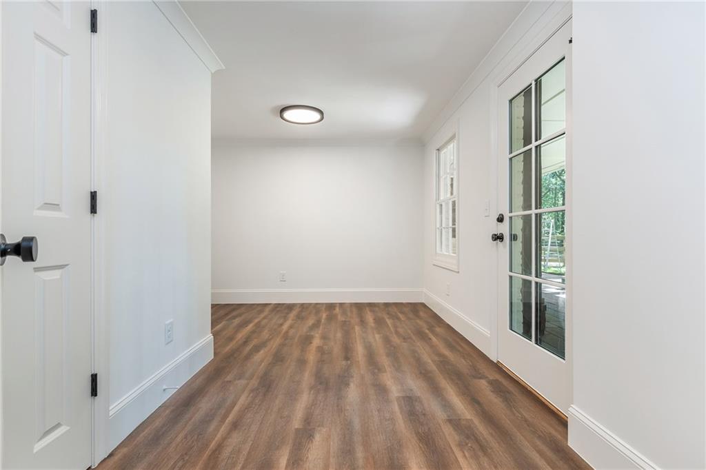 Bright empty room with brown wood-look floors and a glass-paneled exterior door.