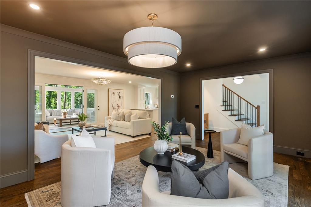Staged sitting room with white armchairs, a black round coffee table, and a large drum pendant light.