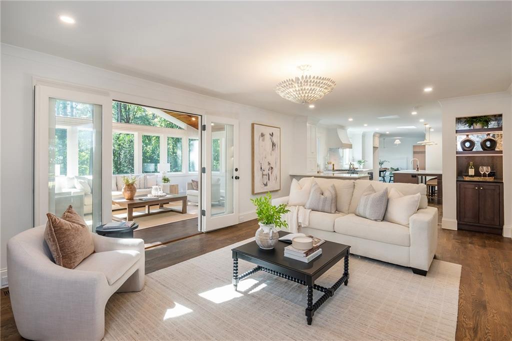 Living room with white sofas, a black coffee table, and glass doors to a sunroom.