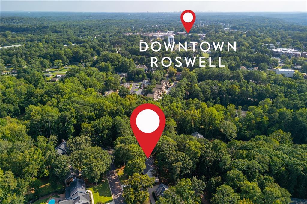 Aerial view of a wooded Roswell neighborhood, with map pins marking the property and downtown.