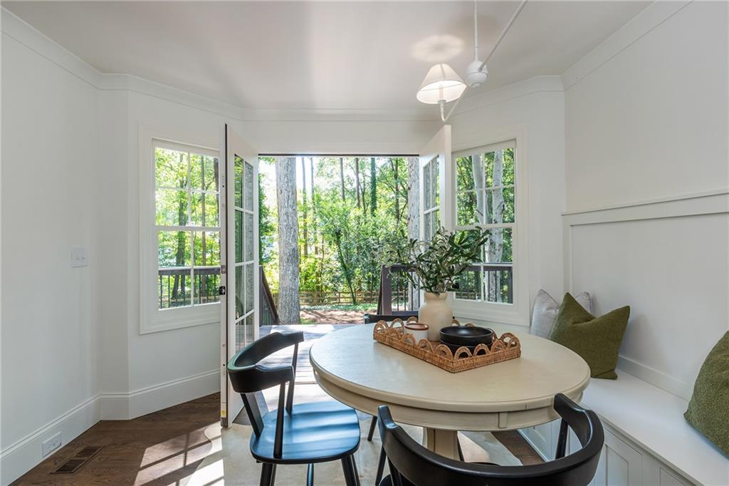 Dining nook with a round table and French doors opening to a wooded deck.