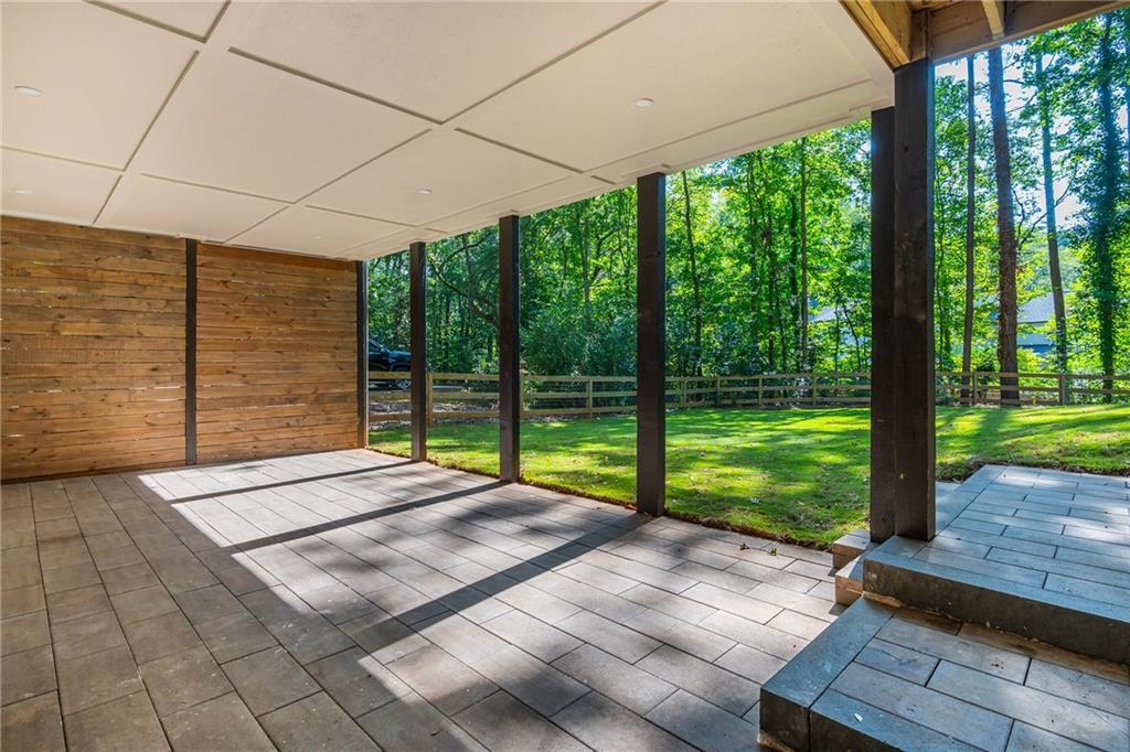Covered tiled patio opening onto a sunny, tree-lined yard.