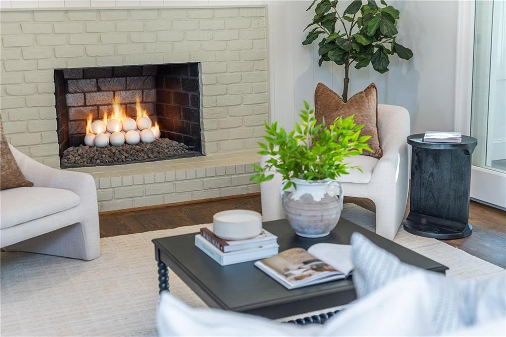 Living room with a white brick fireplace, upholstered chairs, and a black coffee table.