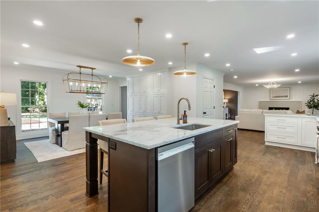 Open-plan kitchen with a marble island, dark cabinetry, and dining and living areas beyond.