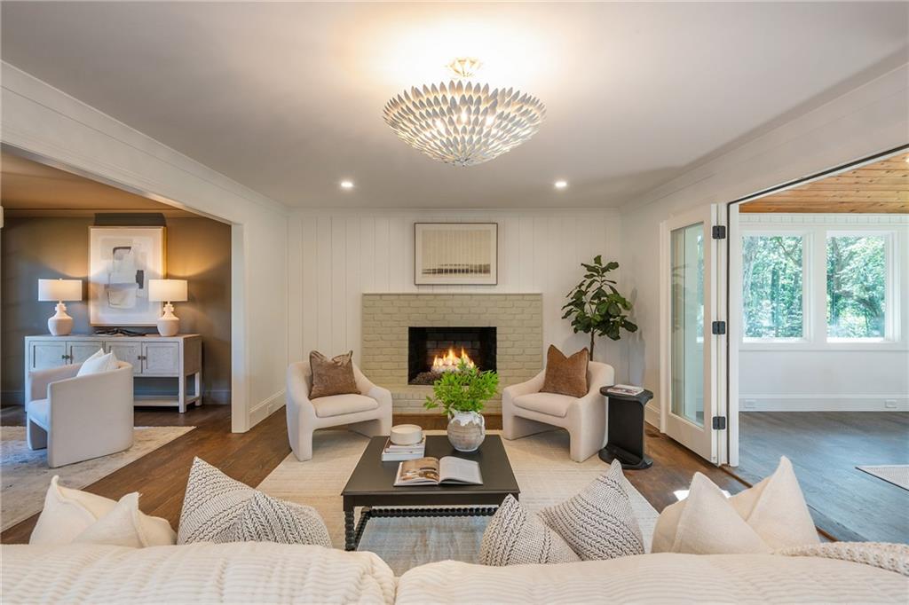 Staged living room with a light brick fireplace, chandelier, and seating around a coffee table.