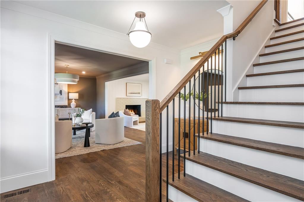 Home entryway with a dark wood staircase overlooking a staged living room and fireplace.