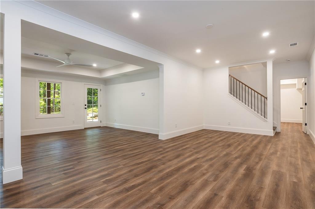 Vacant living area with wood-look floors, recessed lighting, and a staircase.