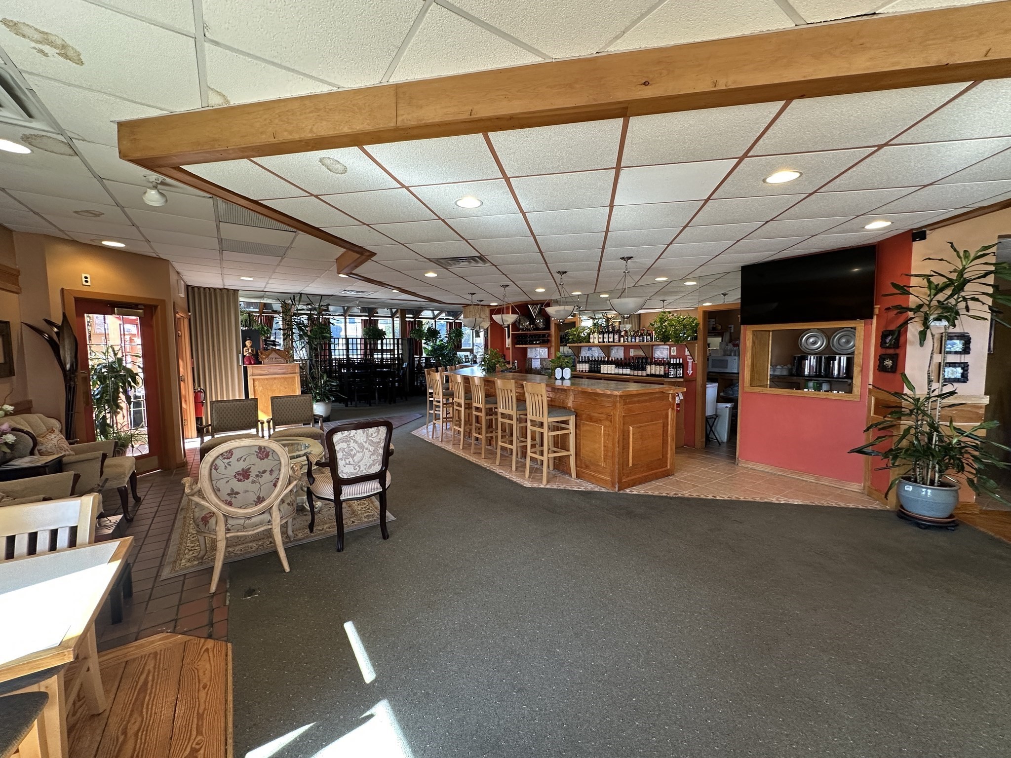 Restaurant interior with a wooden bar, wine shelves, stools, and lounge seating.