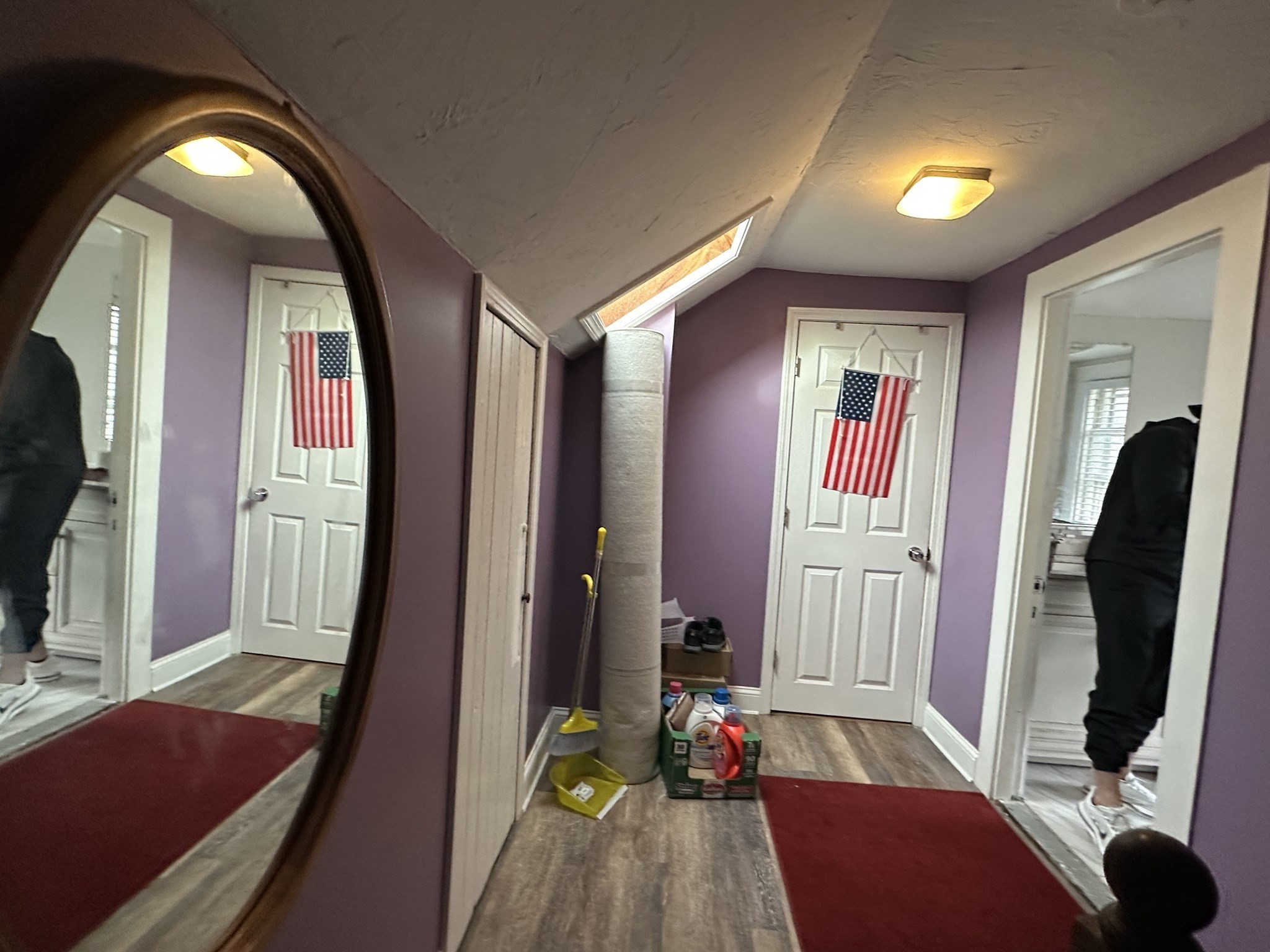 Hallway with purple walls, a skylight, red runners, and an American flag on the far door.