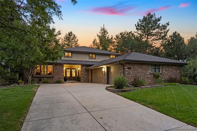 Brick home with an attached two-car garage and broad driveway, photographed at dusk.