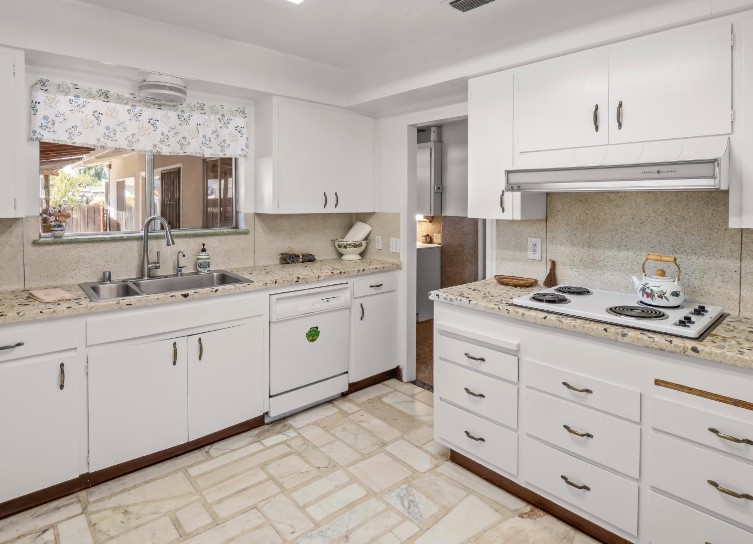 Kitchen with white cabinets, a window-side double sink, and a built-in electric cooktop.