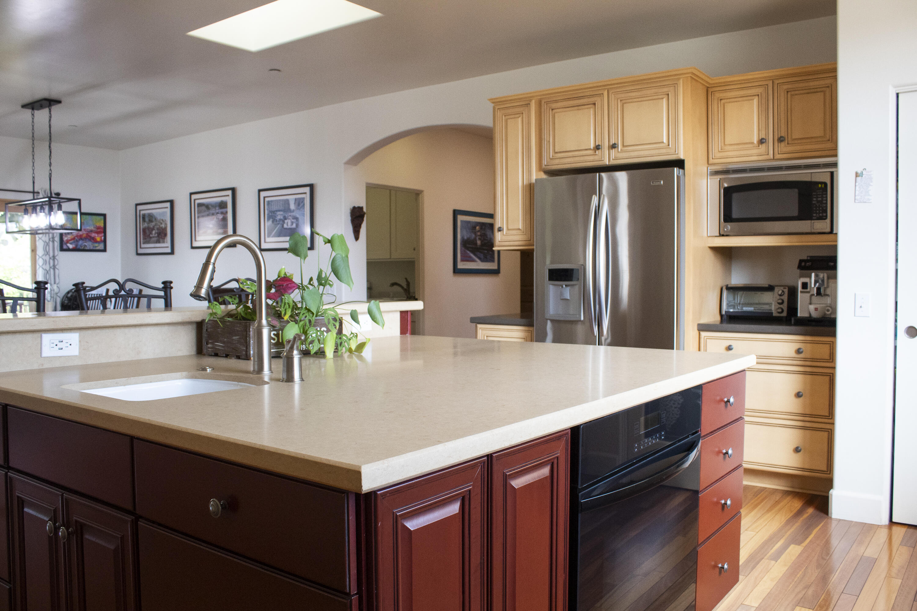 Kitchen with a large stone-topped island, dark wood cabinets, and stainless steel appliances.