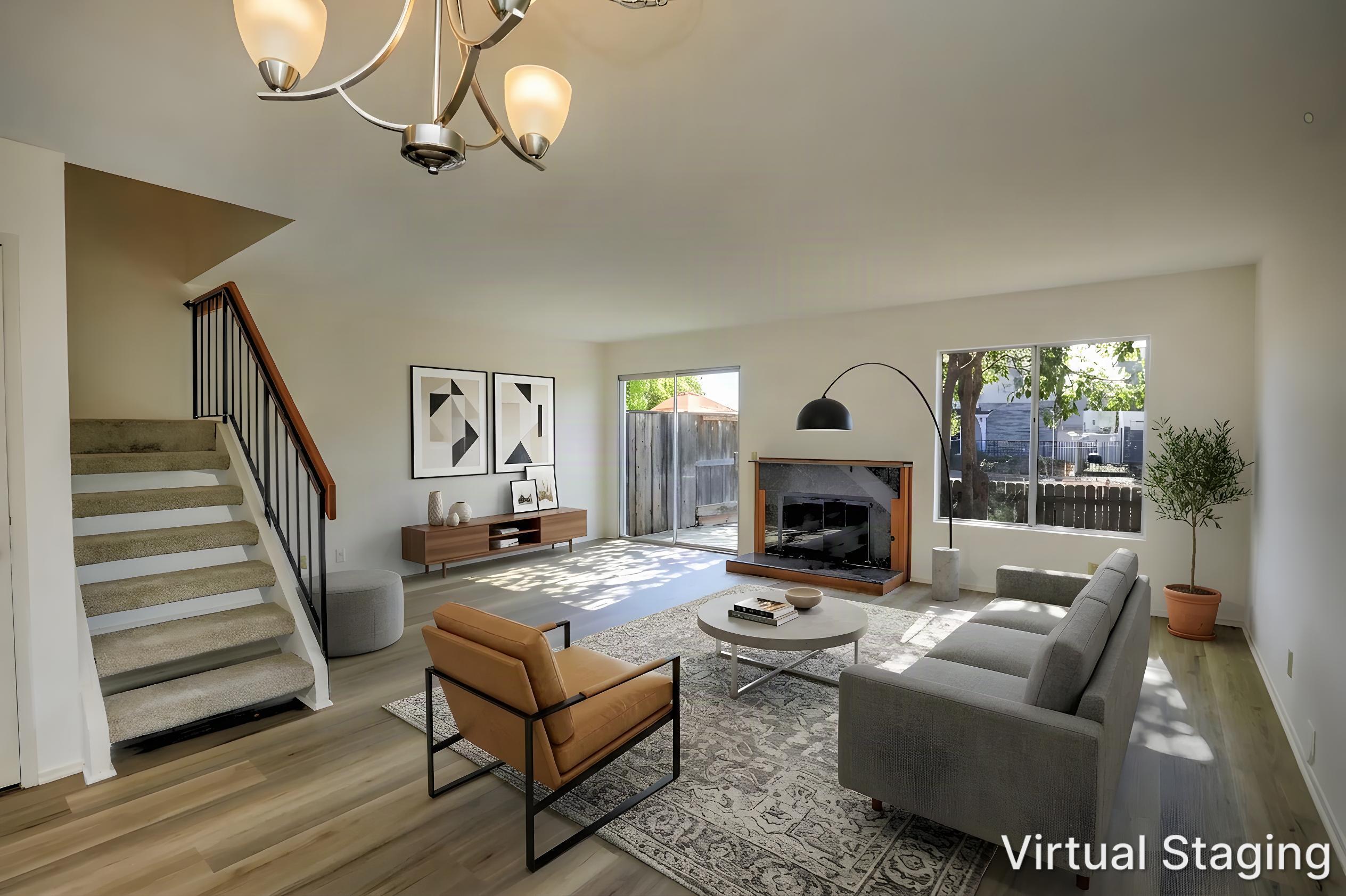 Virtually staged living room with a fireplace, staircase, gray sofa, and sliding glass doors.
