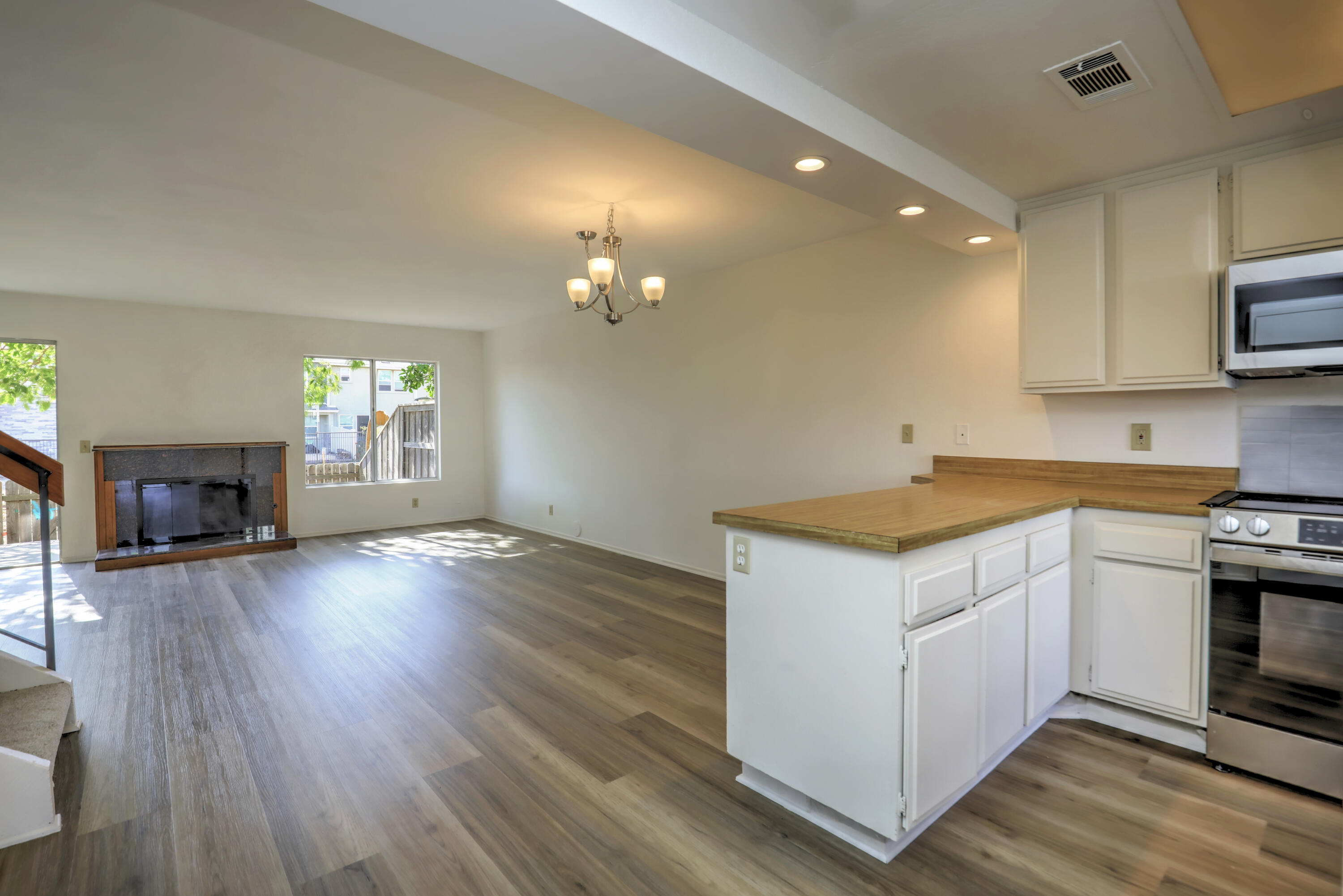 Open living room and kitchen with a fireplace, wood-look floors, and a wood-counter island.