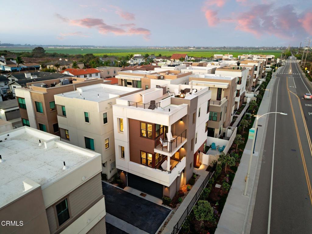 Aerial view of modern townhomes beside a road, with agricultural fields beyond.