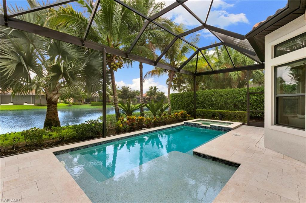 Swimming pool beneath a screened lanai, with tropical palms and a lake beyond.