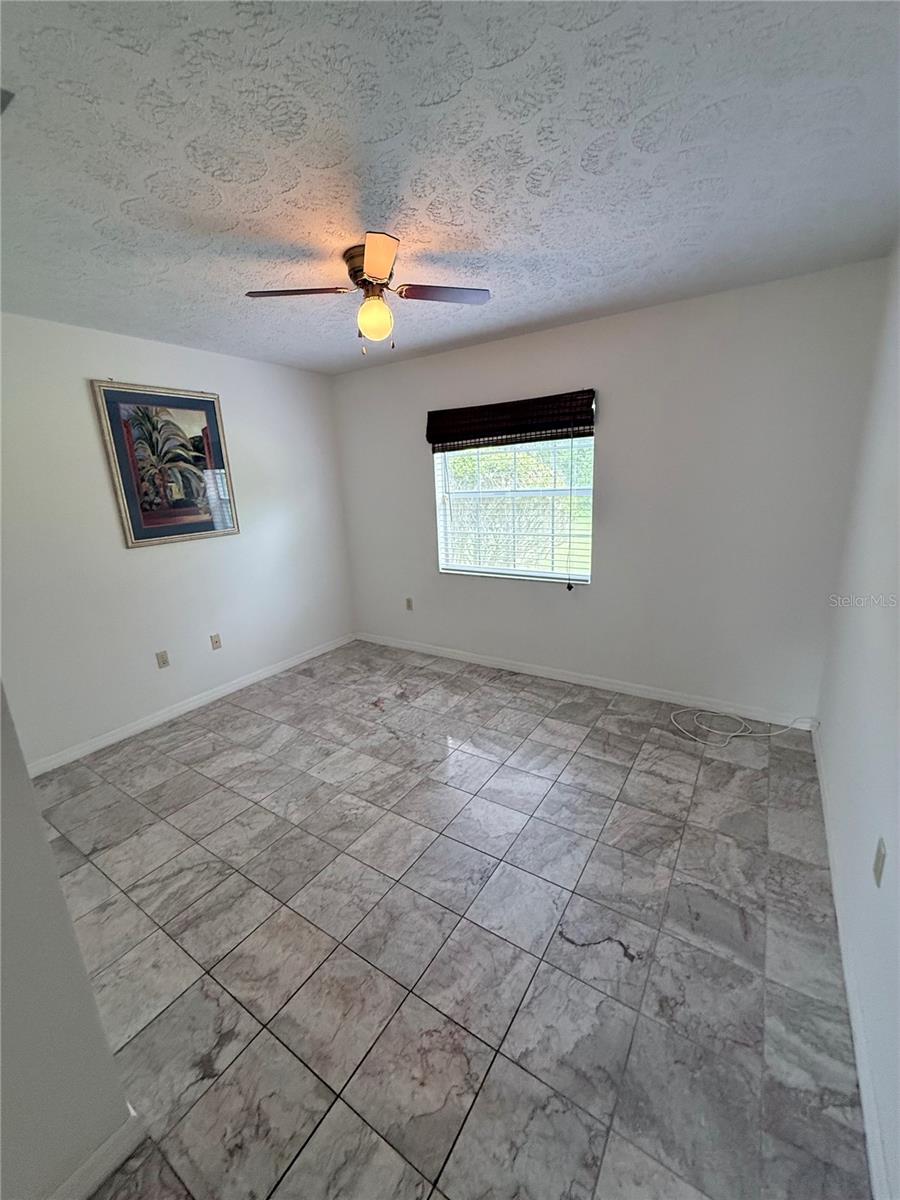 Empty room with marble-pattern tile floors, a window with blinds, and a ceiling fan.
