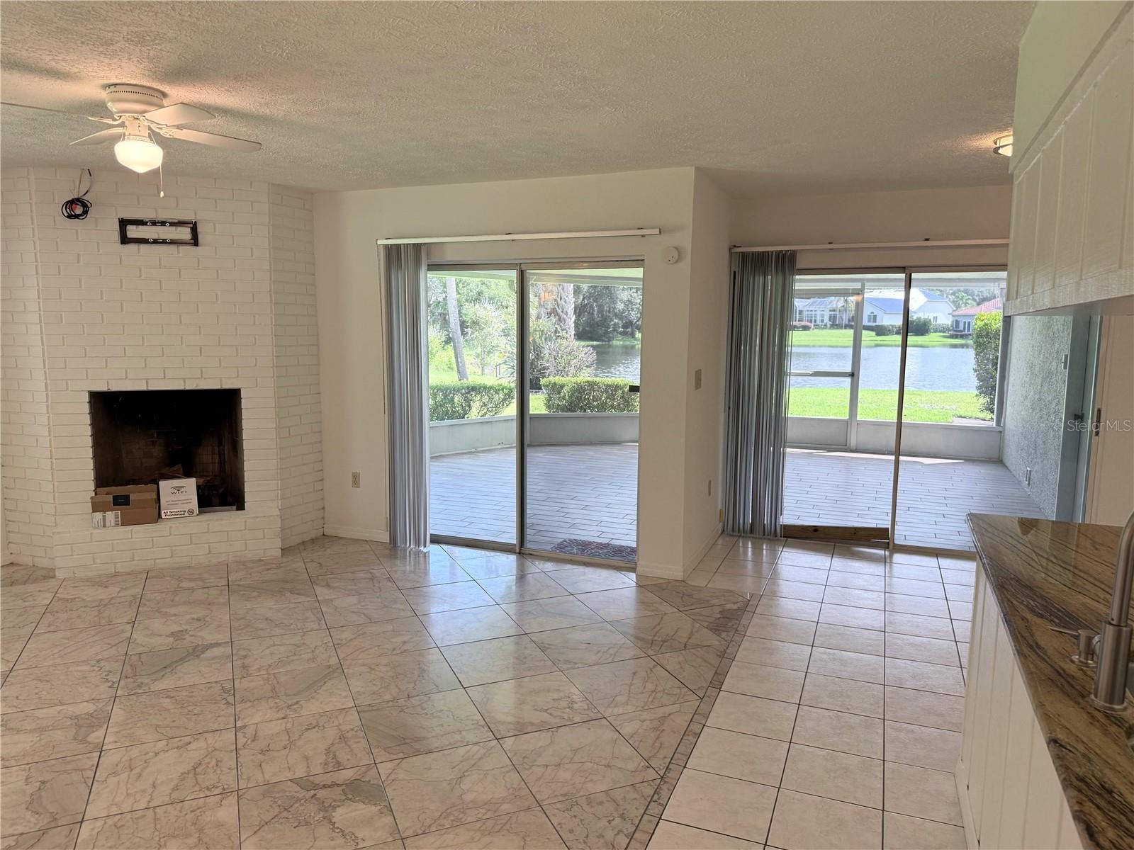 Unfurnished living room with a white brick fireplace and sliding doors overlooking the water.