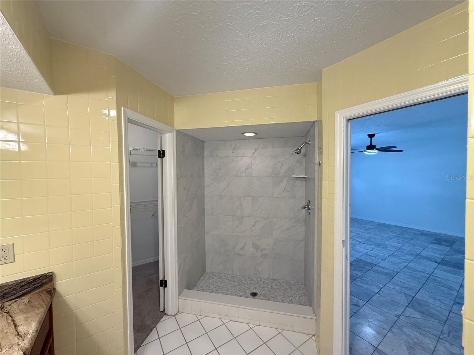 Bathroom with a spacious gray marble-look tiled walk-in shower and mosaic shower floor.