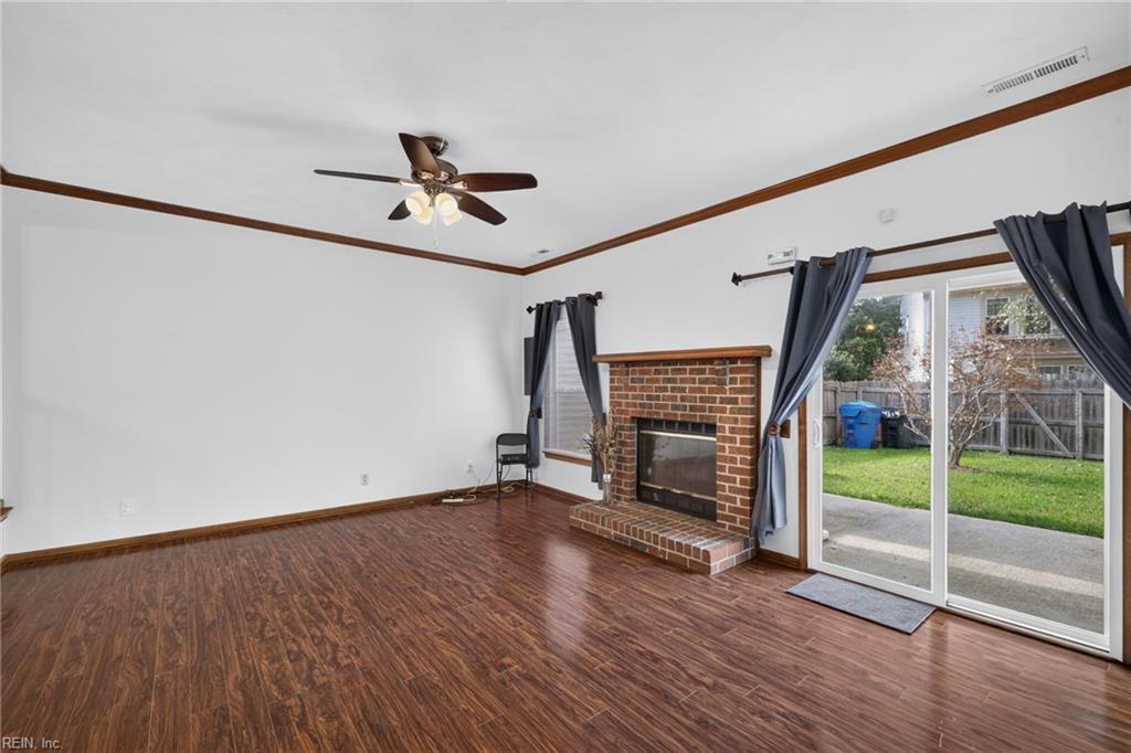 Mostly empty living room with a brick fireplace and sliding glass doors to the backyard.