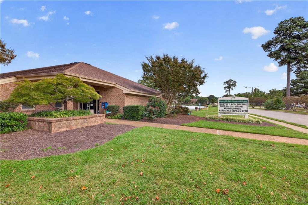 Brick community association building with landscaped grounds and a roadside sign.