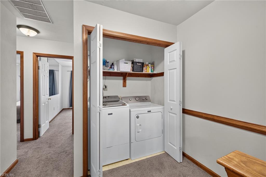 Laundry area with a white washer and dryer in a wood-trimmed closet.