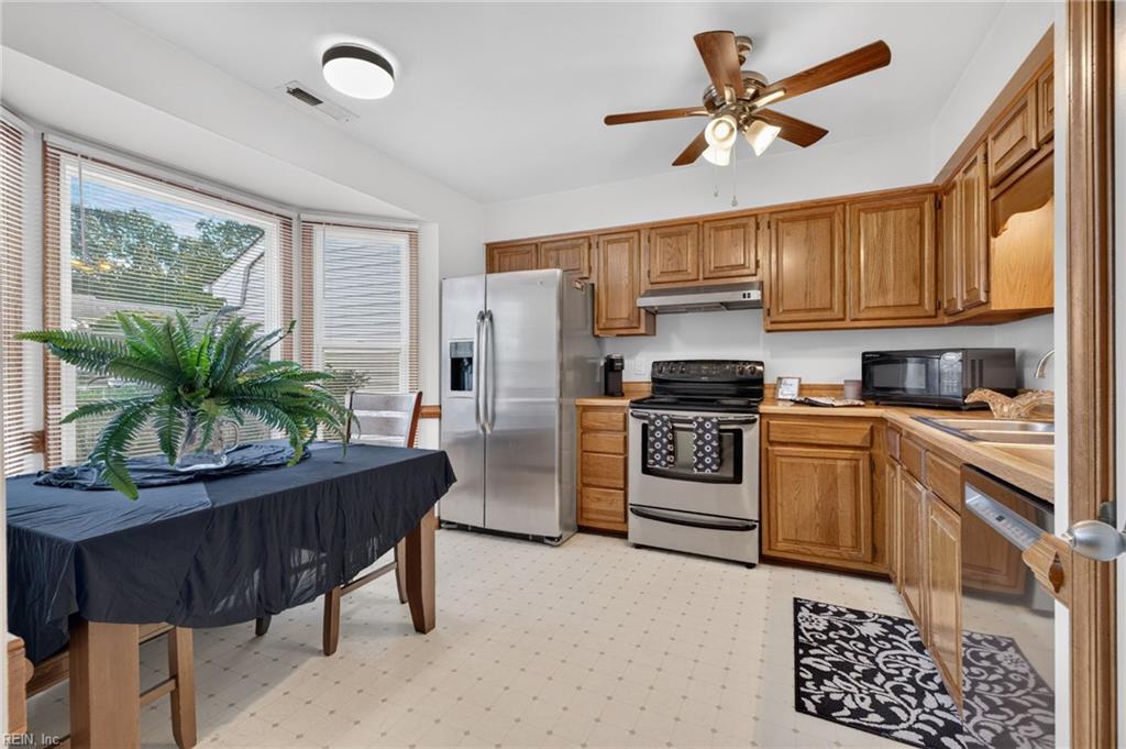 Kitchen with wood cabinets, stainless steel appliances, and a dining table beside large windows.