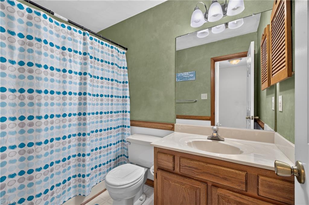 Bathroom with a circular-pattern shower curtain, oak vanity, and green walls.