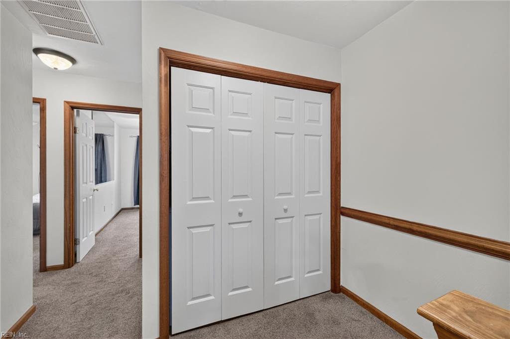 Hallway with white paneled closet doors, gray carpet, and dark wood trim.