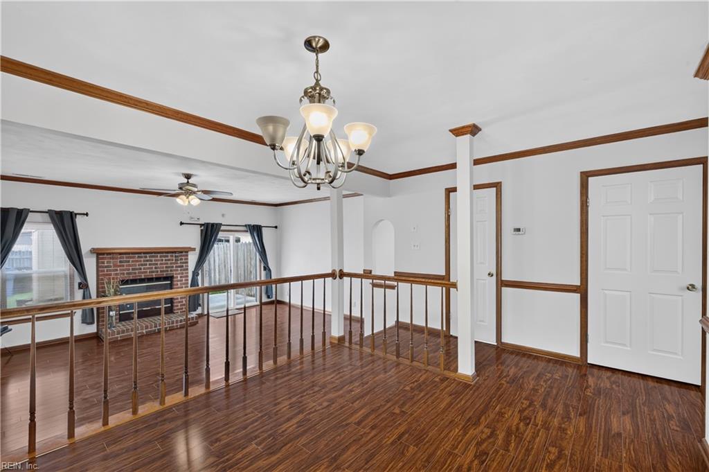 Hardwood-floored landing overlooking a living room with a brick fireplace and dark wood railing.