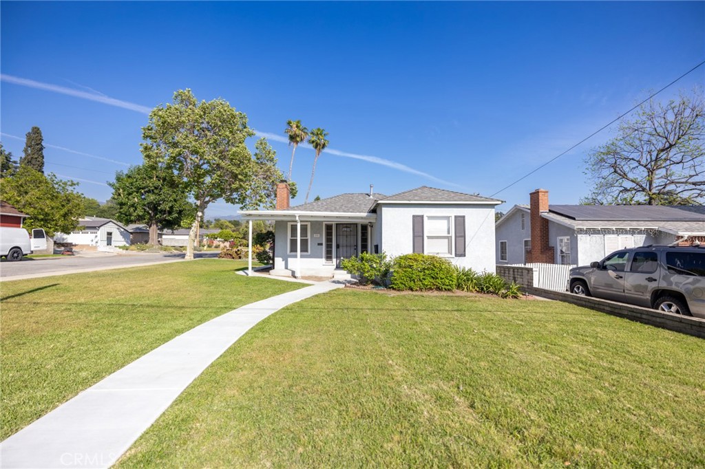Single-story white house with a covered porch, broad lawn, and curved concrete walkway.