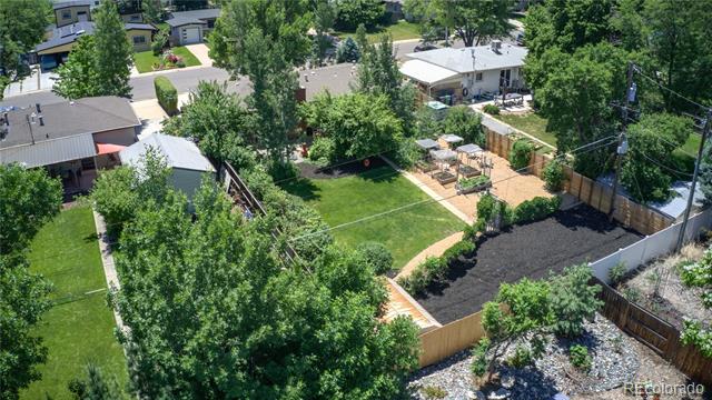 Aerial view of a fenced backyard with lawn, paths, patio seating, and garden beds.