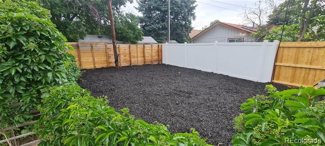 Fenced backyard with a large mulch-covered area and white privacy fence at the back.