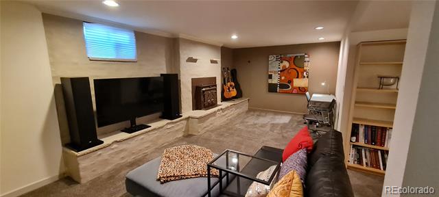 Basement living room with large television, stone fireplace, sectional sofa, and built-in shelving.