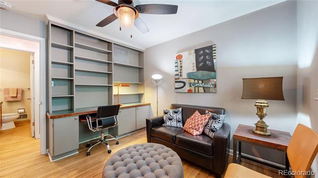 Home office with built-in shelving and desk, leather loveseat, and tufted ottoman.