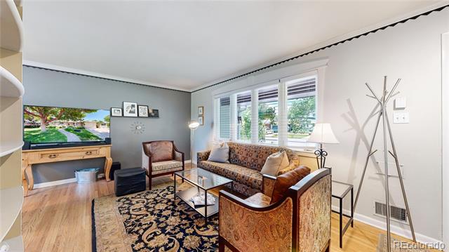 Living room with patterned seating, an ornate rug, hardwood floors, and large daylight-filled windows.