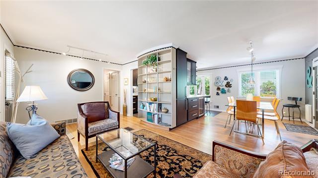 Open-plan living and dining room with hardwood floors, built-in shelving, and large windows.