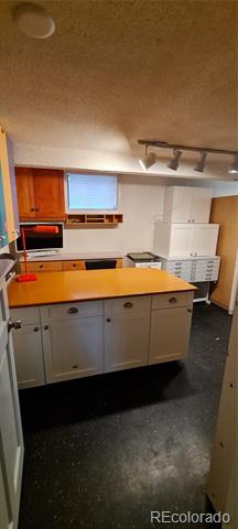 Kitchen with orange countertops, white cabinets, and a built-in microwave.