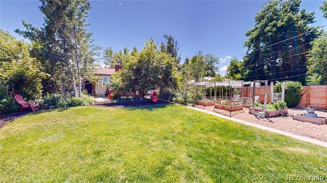 Backyard with a broad lawn, mature trees, and a pergola-covered patio.