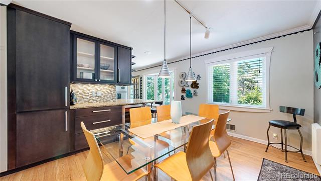 Dining area with a glass-top table, orange chairs, dark cabinetry, and a large window.